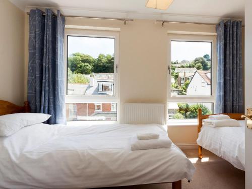a bedroom with two beds and two windows at Oakridge in Salcombe