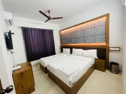 B Six Hotel في بانغالور: غرفة نوم بسريرين ومروحة سقف