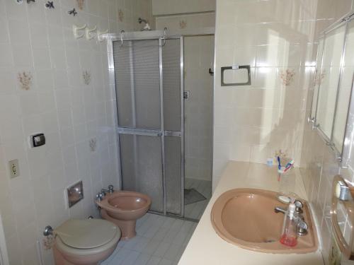 a bathroom with a shower and a toilet and a sink at Apartamento Pitangueiras in Guarujá