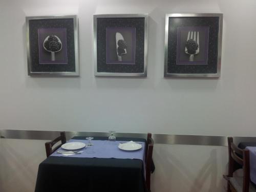 a table with three pictures on the wall and a table with plates at Residencial Santa Clara in Fátima