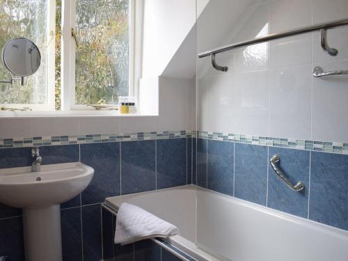 a bathroom with a bath tub and a sink at Coachman's Cottage in Pencombe