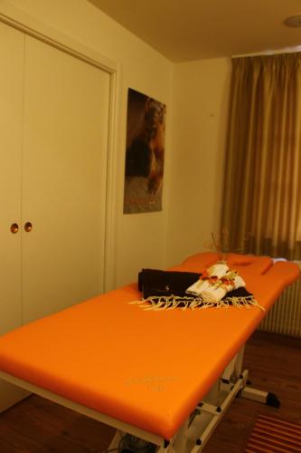 an orange table in a room with a bed at Alpen Hotel Eghel in Folgaria