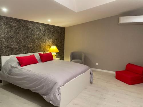 a bedroom with a bed with red pillows and a red chair at Les Meublés de Lassou Gîte in Lombers