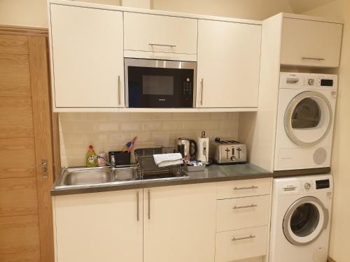 a kitchen with a sink and a microwave at London Luxury 2 bed studio 4 mins from Ilford Stn - FREE parking, WiFi, garden access in Ilford