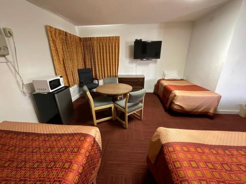 ein Hotelzimmer mit 2 Betten, einem Tisch und Stühlen in der Unterkunft Kansan Motel in Liberal