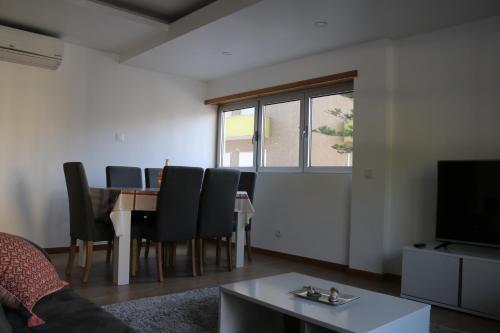 a living room with a table and chairs and a tv at Casa da Fonte Quente in Leiria