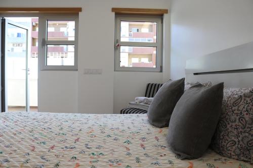 a bedroom with a bed with pillows and windows at Casa da Fonte Quente in Leiria