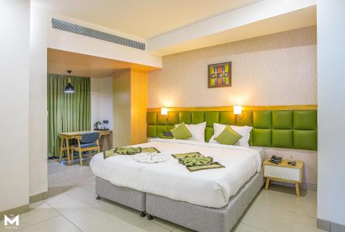 Schlafzimmer mit einem großen Bett mit einem grünen Kopfteil in der Unterkunft THE M HOTEL in Raipur