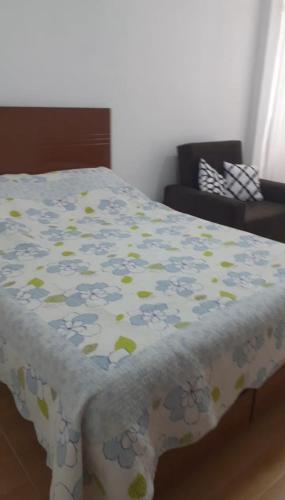 Una cama con una manta con flores. en Departamento Mini 2 pers en Tacna