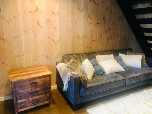 a couch in a room with a wooden wall at Fyri Tunet Hemsedal in Hemsedal