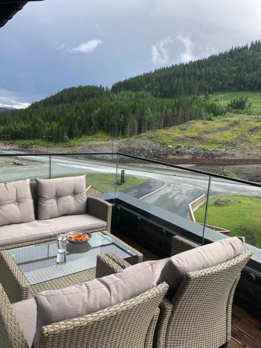 Un balcón con 2 sofás y una mesa de cristal. en Fyri Tunet Hemsedal, en Hemsedal