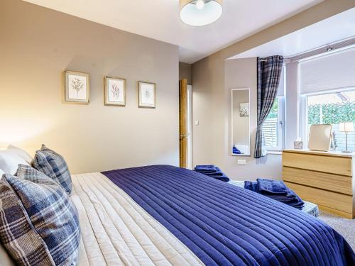 a bedroom with a bed with a blue comforter and a window at Ivy Cottage in Dunoon