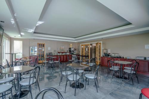 a dining room with tables and chairs and a kitchen at Hotel Quality Suites in Sainte-Anne-de-Beaupré