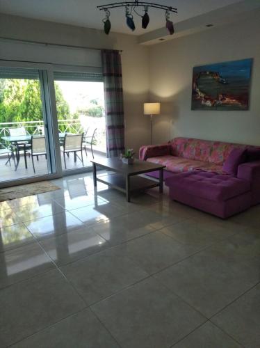 a living room with a purple couch and a table at Cozy villa Vita Lagonisi in Kalívia Thorikoú