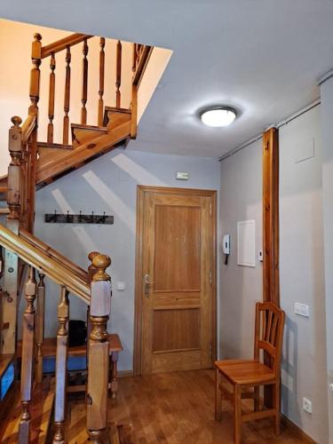 a hallway with a wooden staircase and a wooden chair at Espot Natura - Apartament de muntanya al PN Aigüestortes i Sant Maurici in Espot
