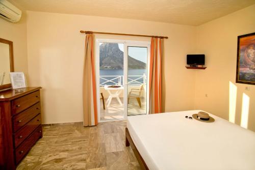 a bedroom with a bed and a door to a balcony at Acropolis Hotel in Masouri