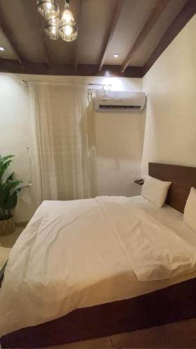 1 dormitorio con cama blanca y ventana en كوخ البيلسان, en Al Shafa