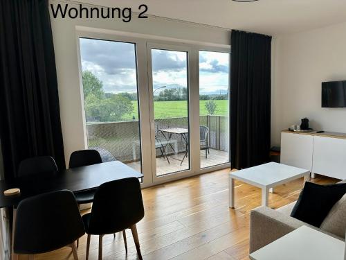 ein Wohnzimmer mit einem Tisch und Stühlen sowie einem Balkon in der Unterkunft Ferienwohnungen Tenner in Jüterbog