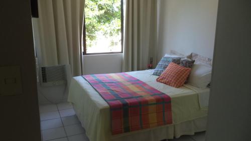 um pequeno quarto com uma cama e uma janela em Apartamento Temporada Maceió em Maceió