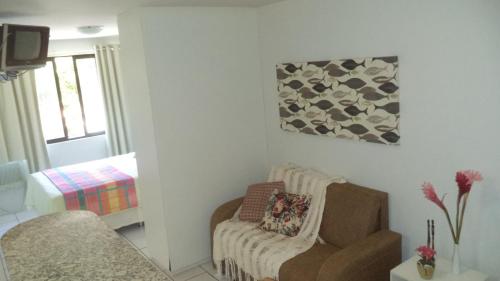 uma sala de estar com um sofá e uma cadeira em Apartamento Temporada Maceió em Maceió