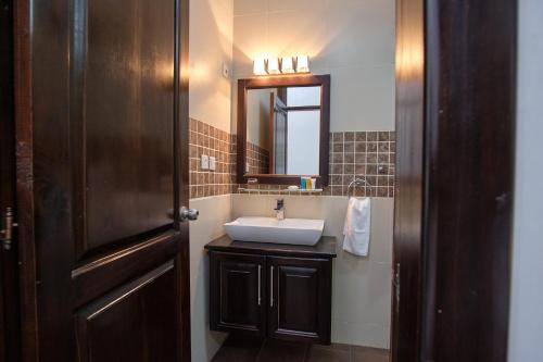 ein Bad mit einem Waschbecken und einem Spiegel in der Unterkunft The Highbridge Guest Lodge in Accra