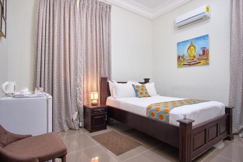 a bedroom with a bed and a chair in it at The Highbridge Guest Lodge in Accra