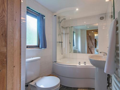 a bathroom with a toilet and a tub and a sink at Heron Barn in Hollingbourne