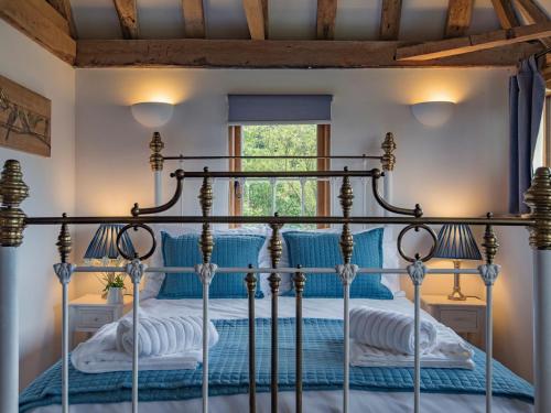 a bedroom with a four poster bed with blue sheets at Heron Barn in Hollingbourne