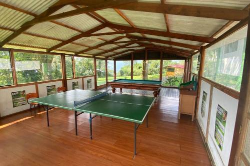 a ping pong table in a room with windows at Confortable cabaña para que disfrute con su pareja in Santandercito