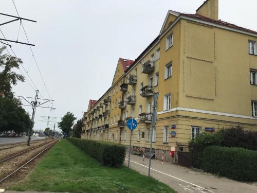 a yellow building next to a street with train tracks at Marymont Metro Apartment in Warsaw
