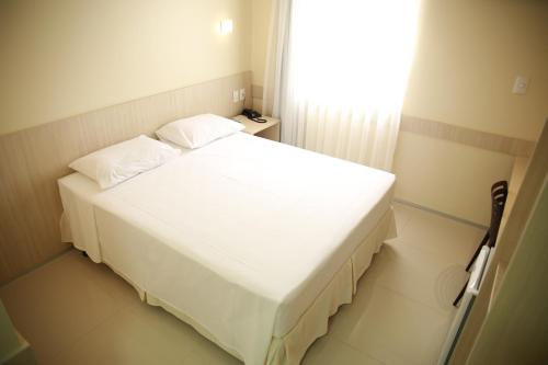 a white bed sitting in a room next to a window at Stay Inn Hotel in Imperatriz