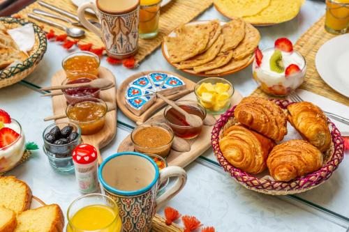 una tavola ricoperta di piatti di paste e altri prodotti per la colazione di Riad Dar Talah a Marrakech