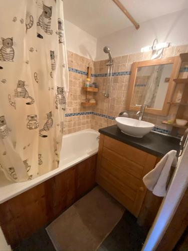 une salle de bain avec une baignoire, un lavabo et un rideau de douche dans l'établissement Appartement face Mont Blanc, à Demi-Quartier