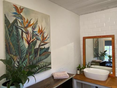 La salle de bains est pourvue d'un lavabo et d'une peinture murale. dans l'établissement Yellowwoods Farm - POOL COTTAGE (self-catering), à Curryʼs Post
