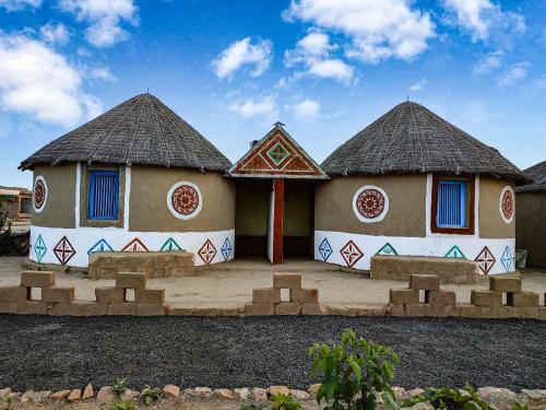 two small huts with blue windows in a yard at RANN STAR VILLAGE STAY in Dhordo