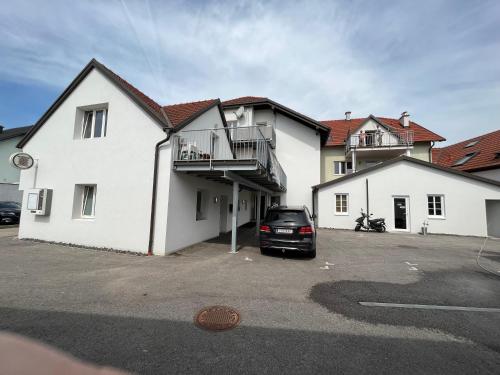 a white house with a car parked in a parking lot at APARTMENTS RATZERSDORFER SEEN in 3100 SANKT PÖLTEN in Sankt Pölten