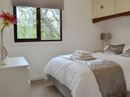 a white bedroom with a bed with towels on it at Josnor Chalet in Benllech