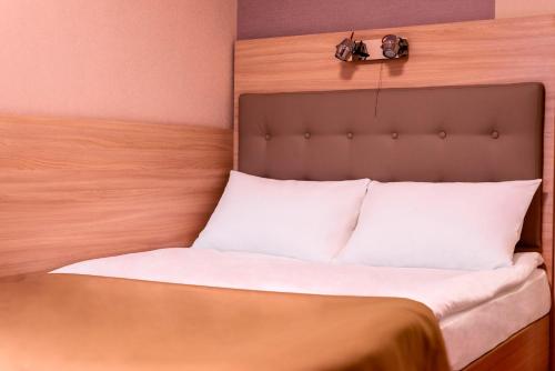 a bed with white pillows and a head board at Tourist Chernivtsi in Chernivtsi