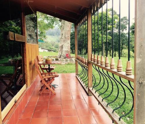 eine Veranda mit einer Bank, einem Tisch und einem Zaun in der Unterkunft Cabañita en el Parque Natural Ecocenter in Santandercito