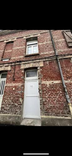 a brick building with a white door and two windows at Richelieu 2 chez Adrien in Saint-Quentin