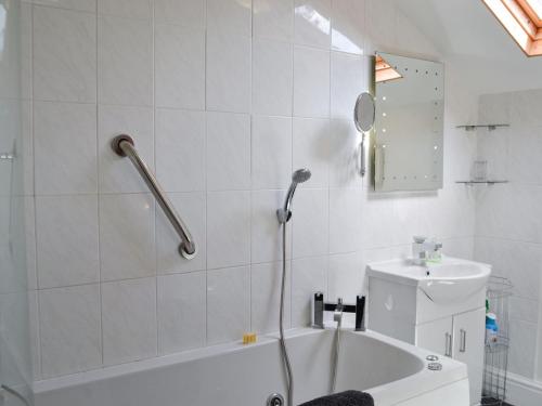 a white bathroom with a shower and a sink at Curlew Cottage in Creetown