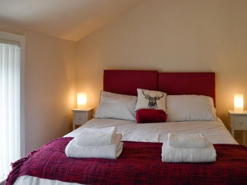 a bedroom with a bed with two towels on it at Curlew Cottage in Creetown
