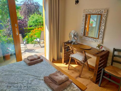 Schlafzimmer mit einem Bett, einem Schreibtisch und einem Spiegel in der Unterkunft Braeside Cottage - Adorable 2 Bedroom Eco-Friendly Character Cottage in Pitlochry