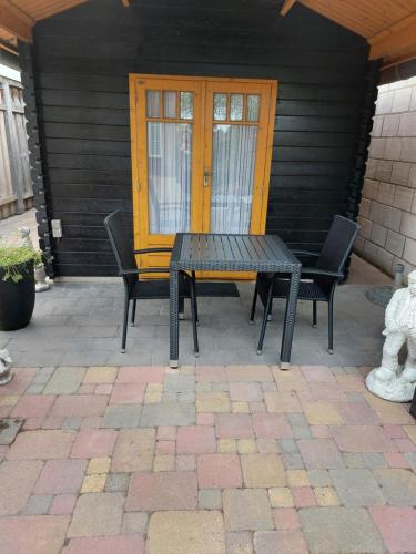 een tafel en stoelen op een patio met een gele deur bij De Poldersteeg 