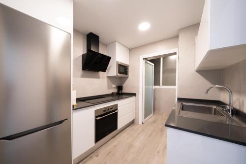 a kitchen with white cabinets and black appliances at Santa Margarita - Benisun in Benidorm
