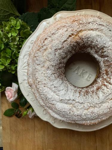 einen Kuchen auf einem Teller auf einem Tisch mit Blumen in der Unterkunft Piccola Corte Antica in Corticelle Pieve