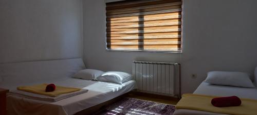 2 Einzelbetten in einem Zimmer mit Fenster in der Unterkunft Guest House Enis in Dubrave Gornje