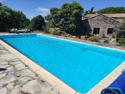 a large blue swimming pool in front of a house at Gîte de Navacelles in Blandas