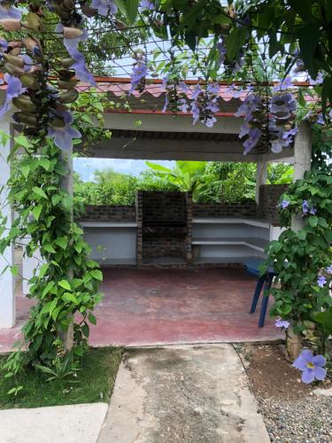 a pergola with purple flowers growing around it at Casa Campo Mi Valle Km9 in Valledupar
