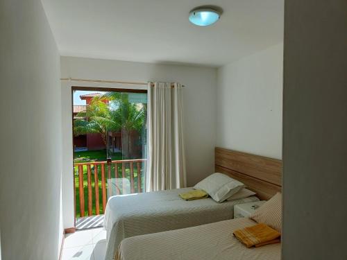 a bedroom with two beds and a window with a balcony at Apto na Praia de Itacimirim H in Itacimirim